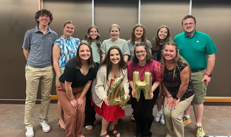 a group of eleven student leaders pose holding balloon letters spelling 4-H