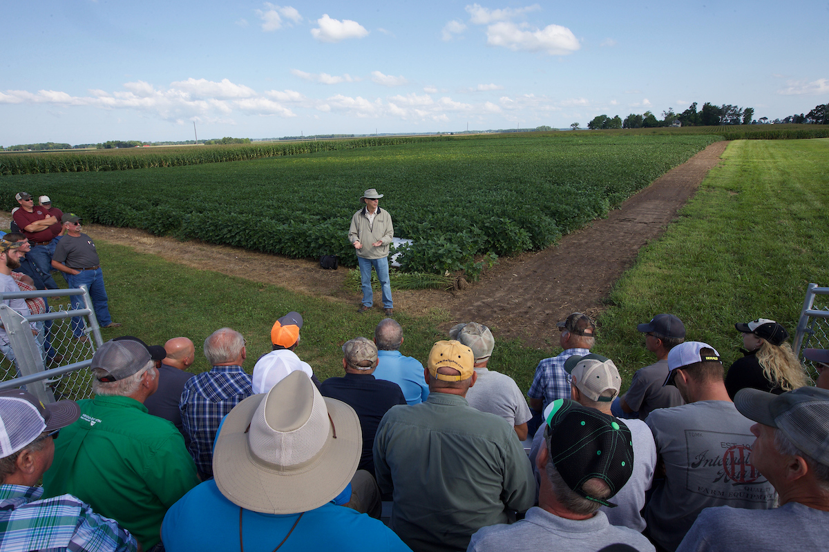 Purdue Extension educator speaking to farmers in front of beans field