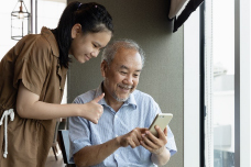 young woman helping an elderly man with his phone