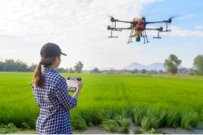 young woman flying a drone outside in an open field