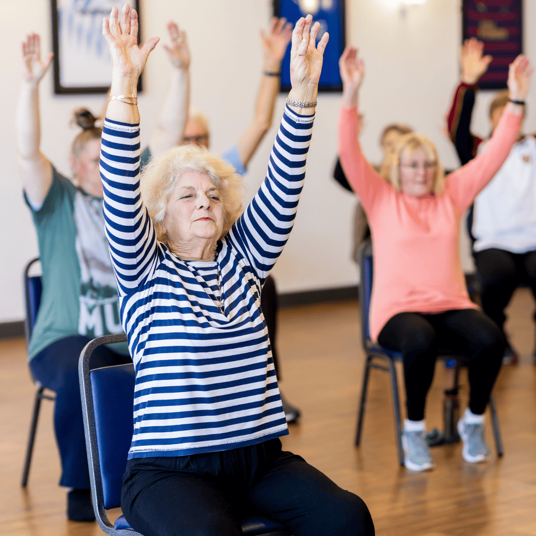Seniors sitting in chairs exercising