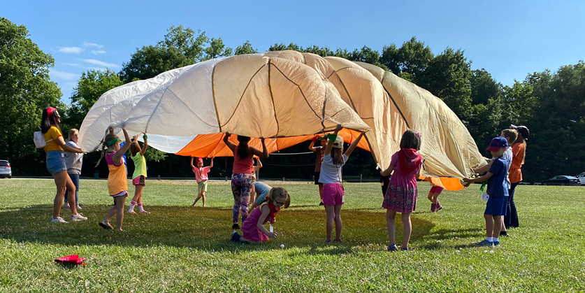 A group of Mini 4-H youth playing with a parachute