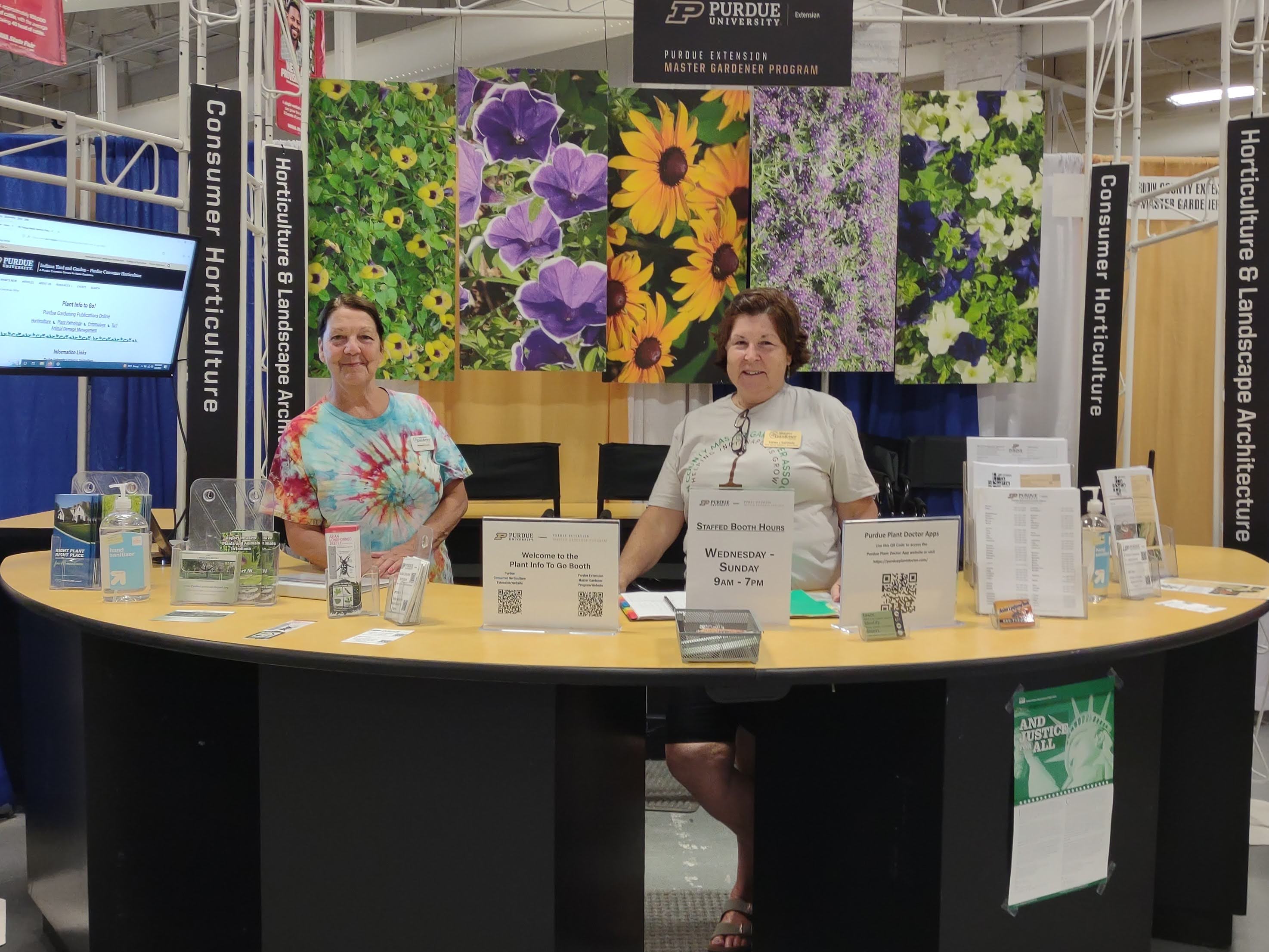 2 women volunteering at an "Ask" desk