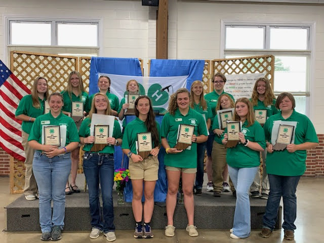 A group of 4-H ambassadors from 2021 receiving their awards.  They are all wearing green shirts. 