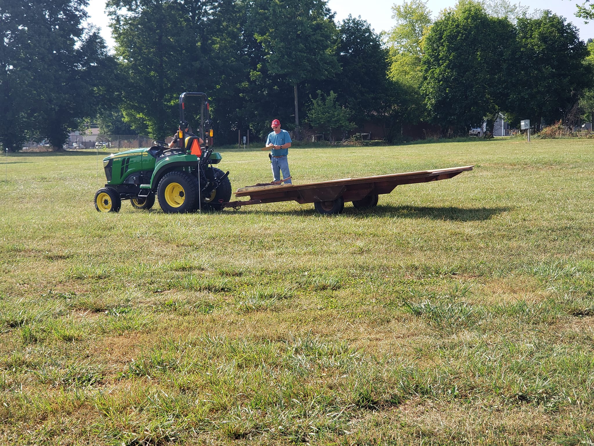 A tractor club member navigating a course with a flat bed trailer attached to John Deere Tractor