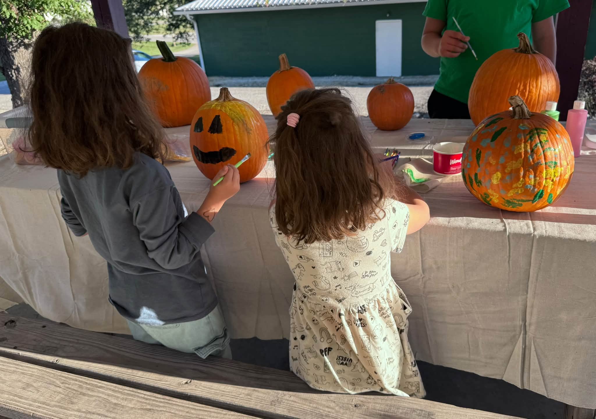 Youth painting pumpkins at a picnic table