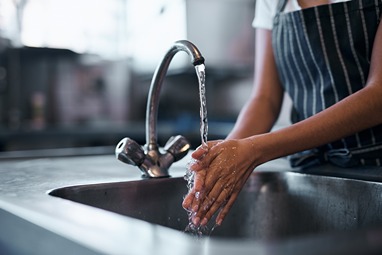 Hands under running sink water