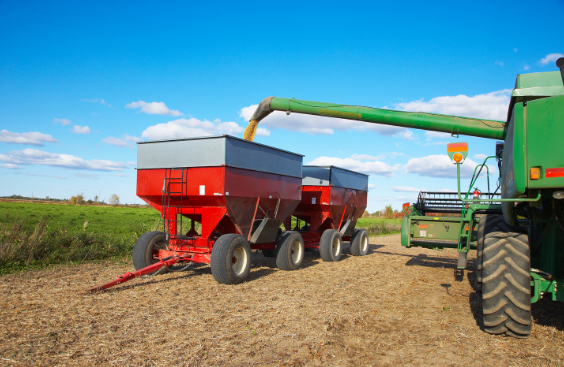 A combine fills a gravity wagon with grain