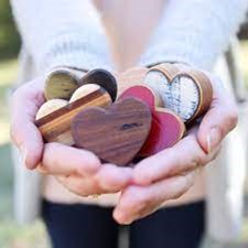 Human hands cupped holding wooden hearts