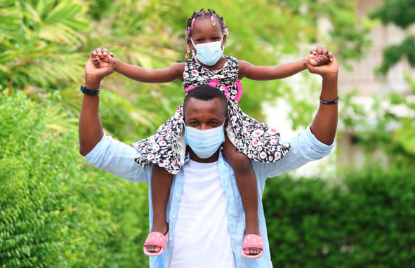 a father holding his daughter on his shoulders