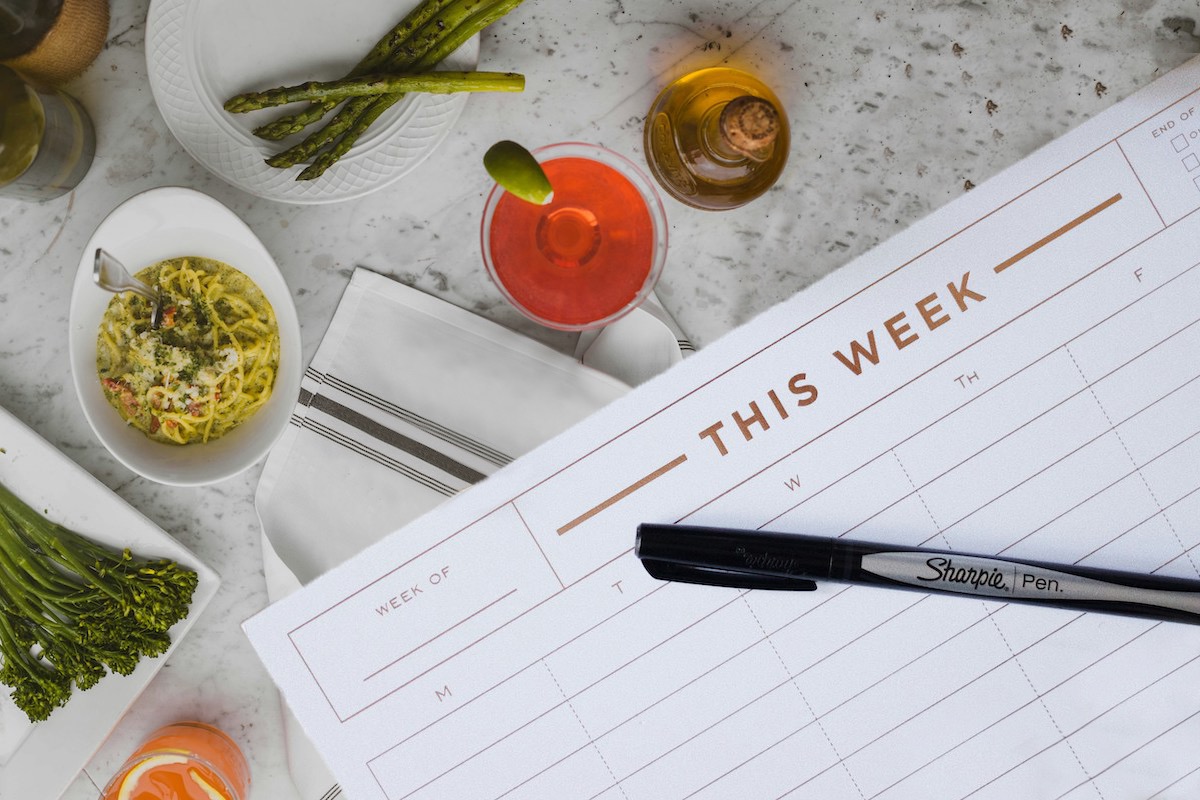 calendar notebook on a table next to food plate