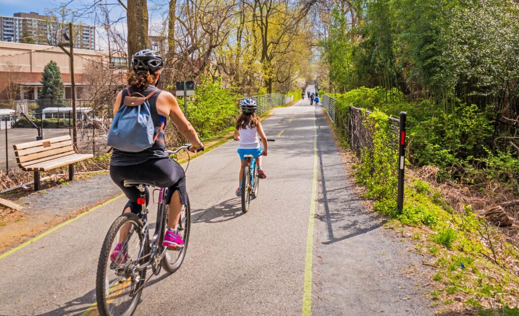 woman riding her bicycle with her daughter on a trail