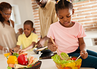 Girl preparing a salad with her family