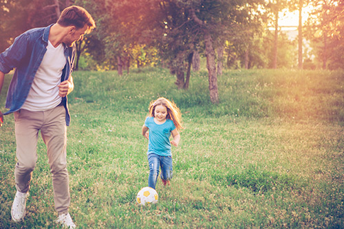 Father playing soccer with her daughter