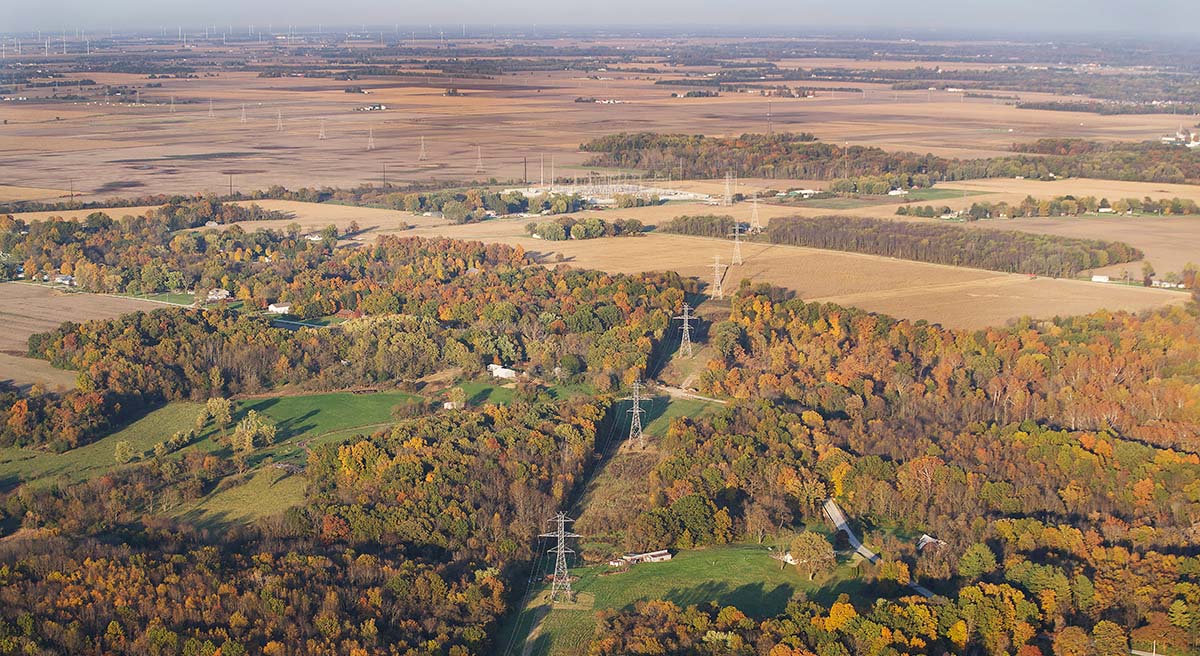 Aerial view of powerlines, trees and farm fields.