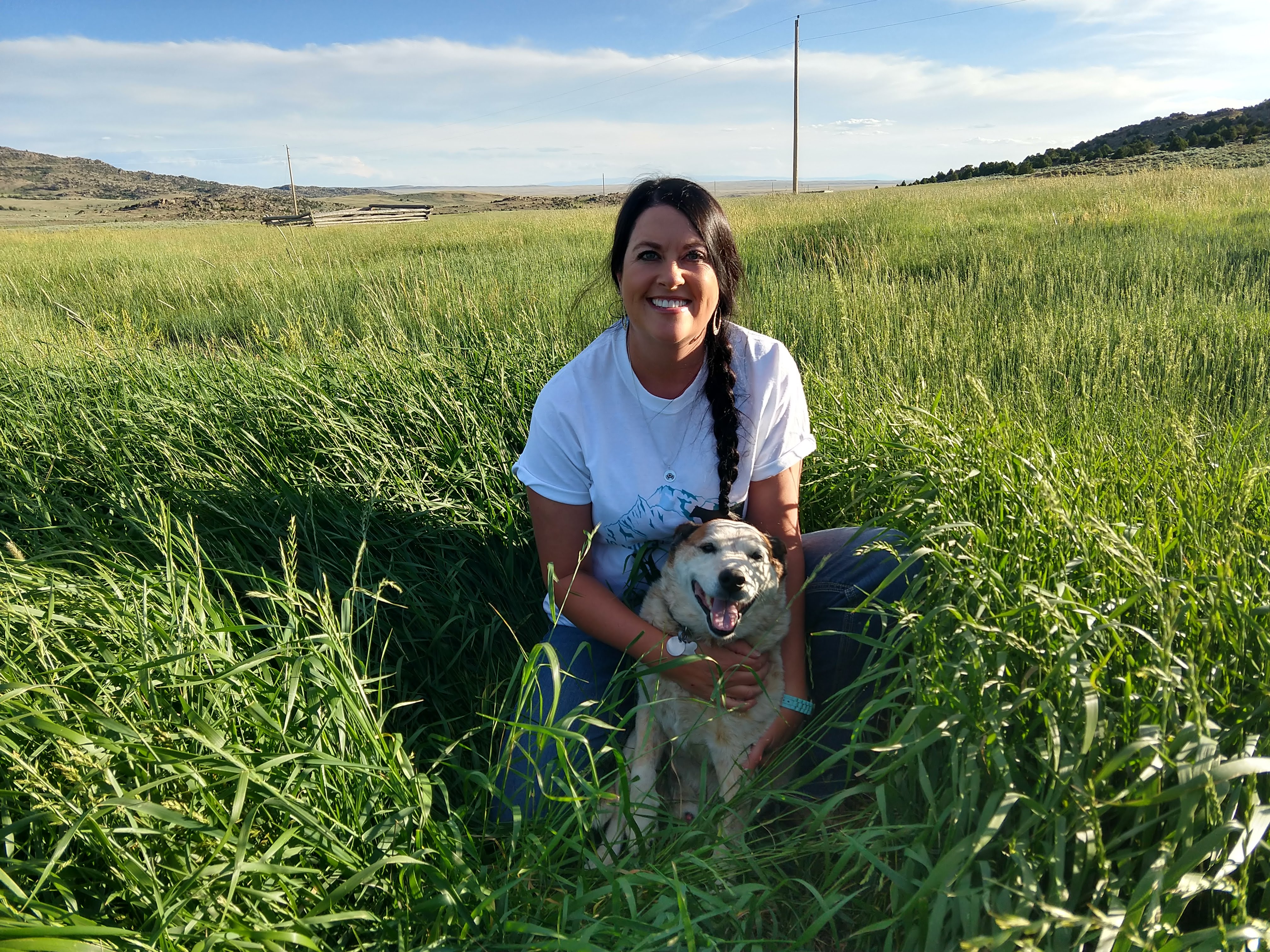 Kacey Atkinson smiling in field with dog, one of the speakers for women in agrictulure conference - held at Purdue University