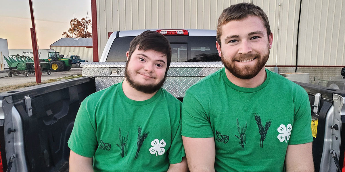 Eddie and Ben, Indiana 4-H'ers, sit on the back of a truck wearing 4-H t-shirts.