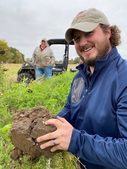 Joe Rorick points out a plant nodule at farmer Dave Brandt’s cover crop field.