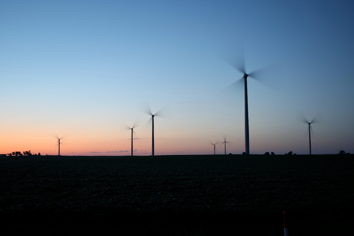 Wind mills in a field with the sun setting