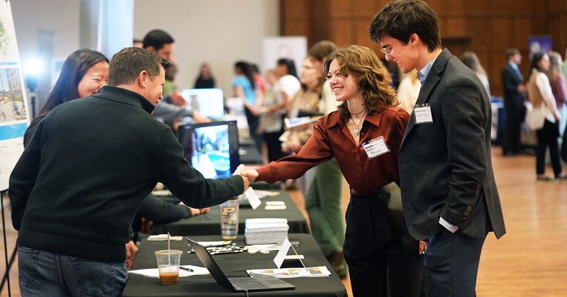 A woman shakes a man’s hand at a career fair