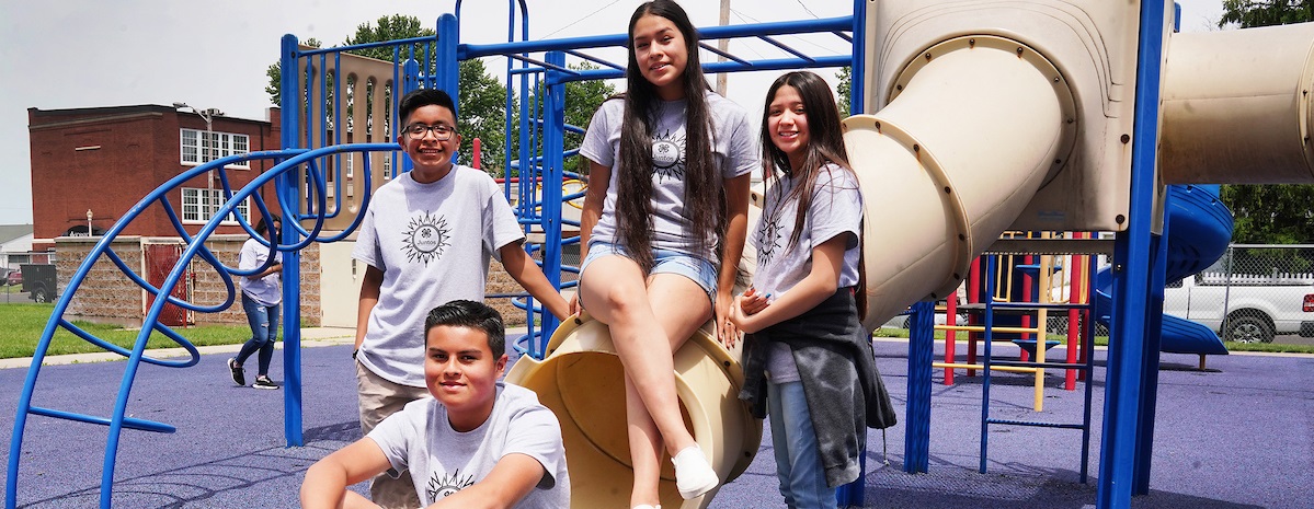 juntos 4-H youth sitting on a playground slide in Indiana