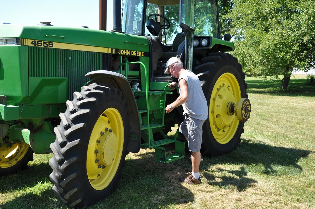 A man uses an added step to climb into a tractor