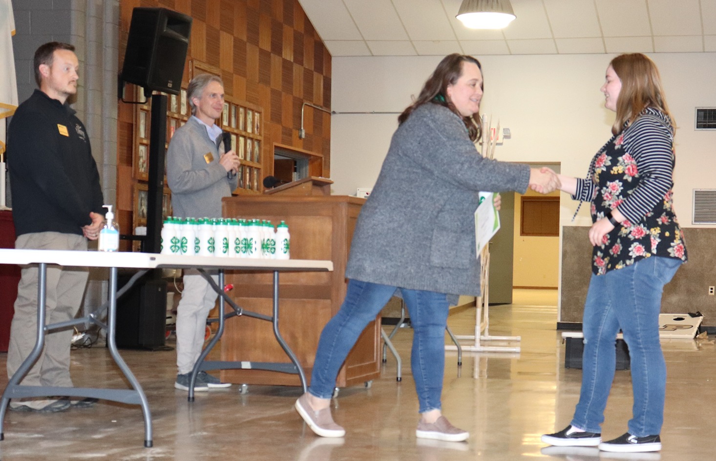 Shelly Powell shakes hands with a 4-H member at an assembly.