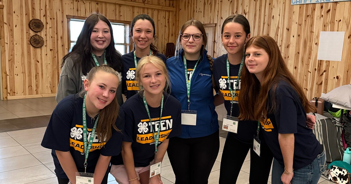 Seven teen girls in 4-H participate in the Tean Leadership weekend and smile for a photo.