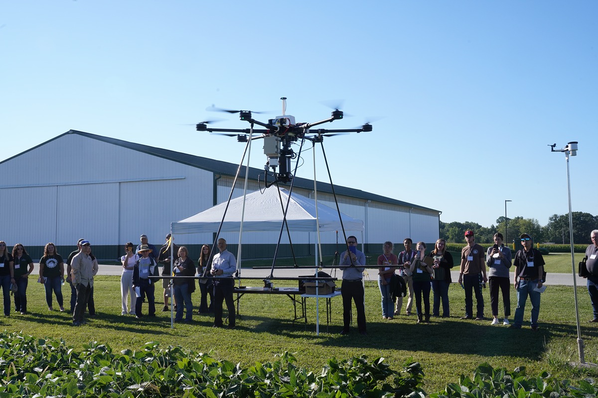 Participants at a digital agriculture showcase watch a drone demonstration. (Tom Campbell) 