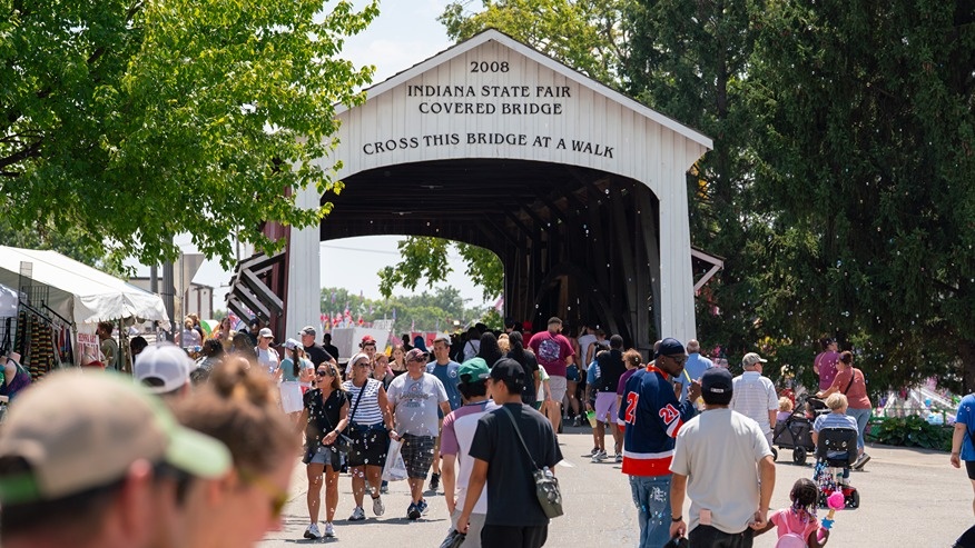 People walk under the Indiana State Fair covered bridge.
