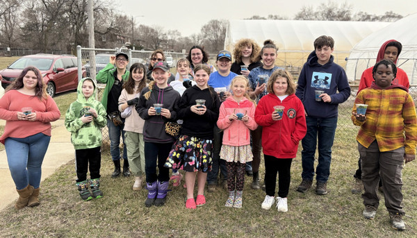 4-H urban ag youth standing outside in front of high tunnels holding plastic cups