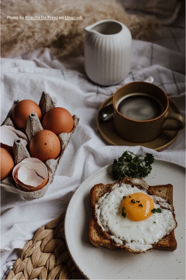 Image of breafast preparation (eggs of carton, a cup of coffee, eggs on a toast and cream) 